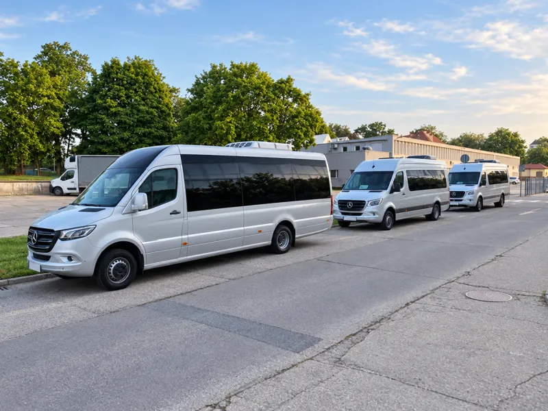 Three silver Mercedes Sprinter minibuses lined up along a street